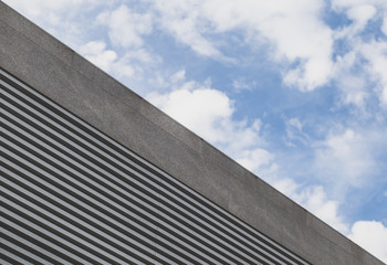 Fototapeta na wymiar From below cloudy sky and modern urban building with striped grid.