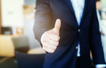 Closeup shot of a businessman in the office showing thumbs up. Success