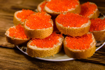 Sandwiches with red caviar on wooden table