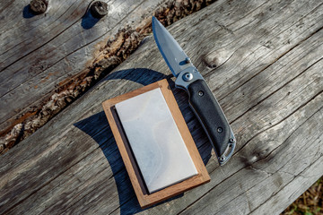 Sharp knife and grindstone on a wooden background.