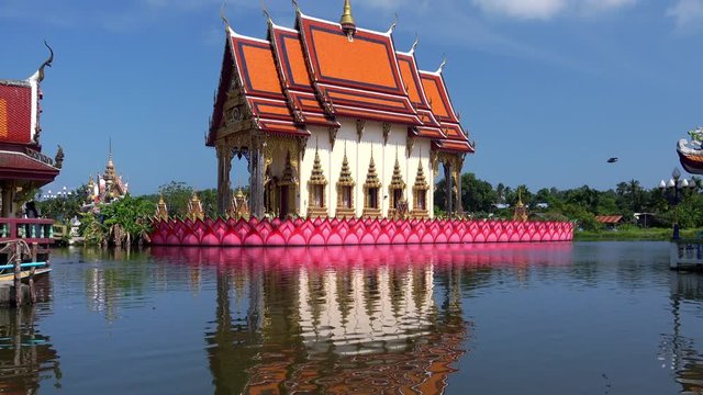 Meditative landscape with beautiful building or Buddhist temple of traditional religious architecture standing in middle of lake or water pond at sunny day. Wat Plai Laem, Koh Samui, Thailand.