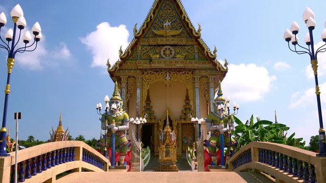 View of bridge leading to ubosot or ceremonial hall of religious Buddhist architecture at Wat Plai Laem temple complex, Koh Samui, Thailand. Beautiful shrine or place of worship. Camera zooms out.