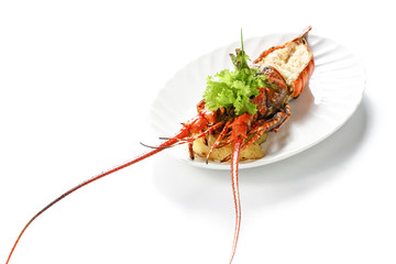 Roasted Lobster with salt, pepper, boiled potatoes and fresh vegetables on white porcelain ovoid plate, Isolated on white background, high angle front side view, Focus at the head of crustacean.