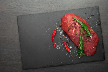 fresh raw meat with rosemary on black slate, on dark background, steak Ribeye
