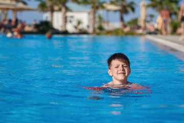 Caucasian child swimming in pool with help of floating sleeves.