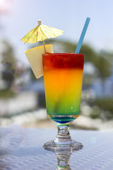 Bright cocktail with umbrella on the background of the pool
