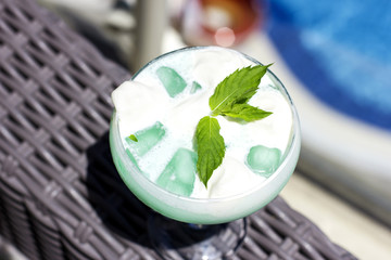 Blue cocktail in a beautiful glass with ice cream and green mint leaves