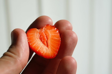 A half a strawberry in hand.