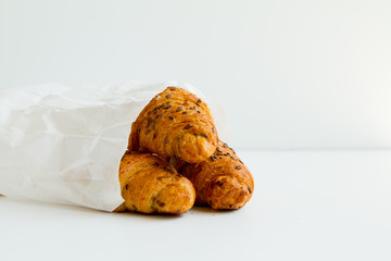 three delicious croissants in a white package on a white table