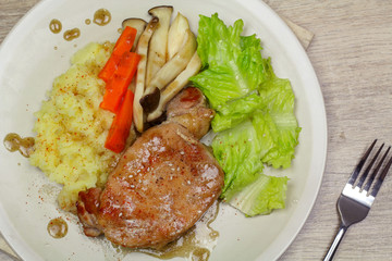 Pork steak with mashed potatoes and mushroom, green lettuce