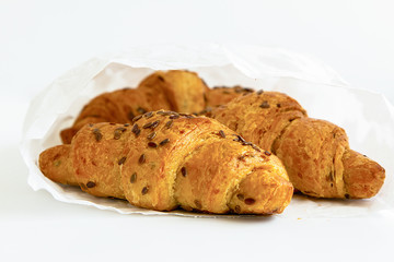 three delicious croissants in a white package on a white table