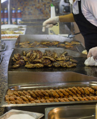 Cook's hand fries meat and burger cutlets on a steaming grill