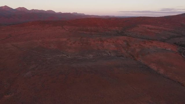 Forward flight with slight turn over red hills at sunset