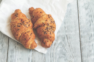two hot croissants on white baking paper on grey wooden background