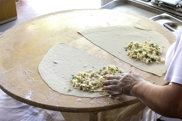 Women cooks a turkish pita 'gozleme' with cheese and greens