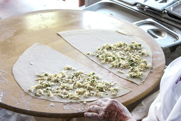 Women cooks a turkish pita 'gozleme' with cheese and greens