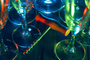 Corkscrew and glasses on a wooden background in a bar under green light