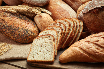 heap of whole and sliced bread on wooden background