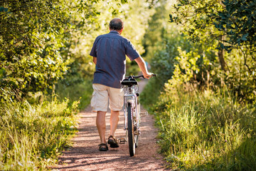 Obraz premium Mature man is walking in forest path
