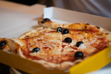 Kinder Margarita Pizza mit Gesicht aus dem Pizzaofen auf einem Teller und in einer Schachtel