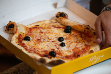 Kinder Margarita Pizza mit Gesicht aus dem Pizzaofen auf einem Teller und in einer Schachtel