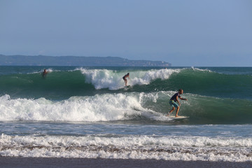 Surfers riding wave and a woman at the forground at Echo Beach Canggu Bali Indonesia