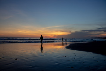 Fototapeta premium Echo beach at sunset. Silhouette of a persons walking by the water. Canggu, Bali, Indonesia.