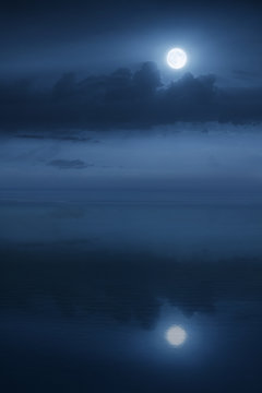 Beautiful night time aerial view of large Blue Moon and Ocean waters