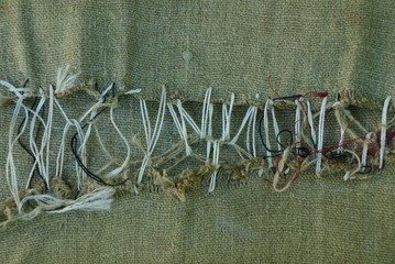 part of a green old ragged fabric sewn with gray thread
