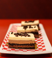 Three layer chocolate mousse cake on a white plate.