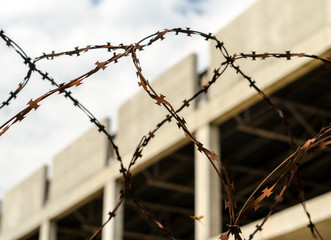 rusty barbed wire fence against the backdrop of an abandoned bui