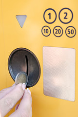 Hand with a coin near the coin acceptor