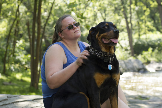 Rottweiler Sitting Attentively With Master On Hiking Expedition Through Forest