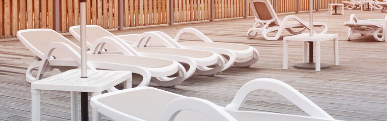 Fototapeta na wymiar Banner Wooden deck beach sea ocean resort sun lounger umbrella hotel pool sky sunrise.