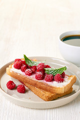Coffee and toast with fresh raspberries on white table