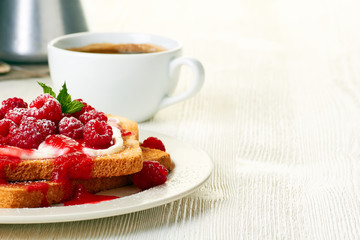 Coffee and toast with fresh raspberries on white table