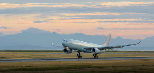 Aircraft landing at YVR at dusk with mountains in the background. - obrazy, fototapety, plakaty