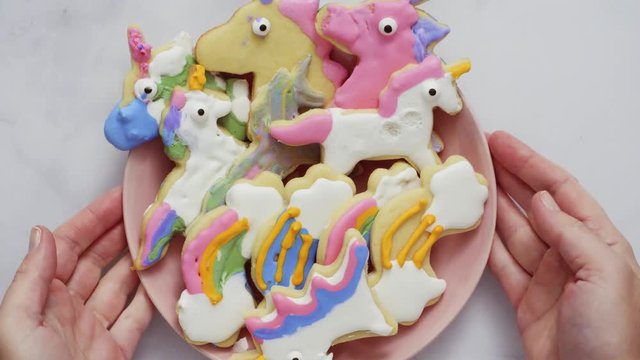 Unicorn shaped sugar cookies decorated with royal icing on pink plate
