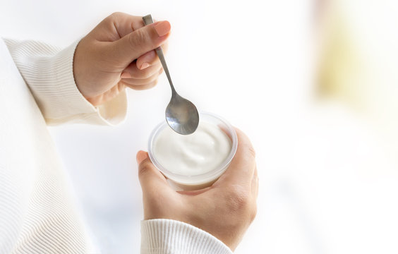 Woman Holding A Cup Of Yogurt And Spoon In Hand.