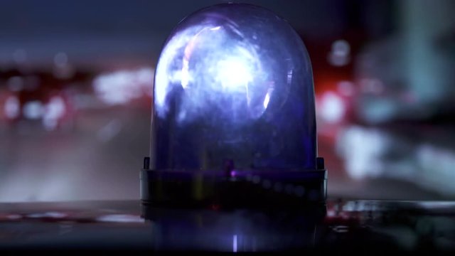 POV driving vehicle with blue flash emergency light on highway at night. Rotating warning beacon mounted on car roof closeup.