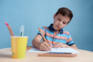 Caucasian boy carefully drawing with colorful pencils.