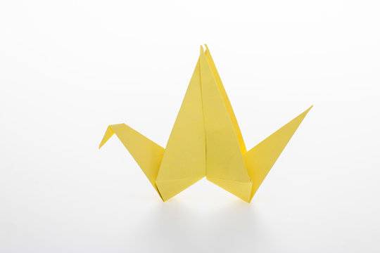 Yellow origami bird on white background.