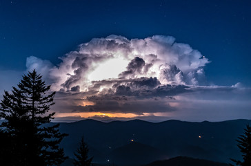 A huge thunderstorm with active lightning lighting up the clouds is seen from the high peak of Spruce Knob in the Appalachian Mountains of West Virginia