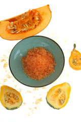 Sea salt with pumpkin extract. Orange sea salt in a blue cup and slices of pumpkin isolated on white background.Pumpkin organic vegan cosmetics.