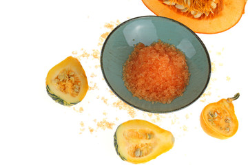 Sea salt with pumpkin extract. Orange  salt in a blue cup and slices of pumpkin isolated on white background.Pumpkin organic vegan cosmetics.