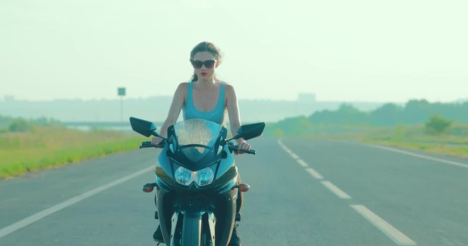 Young girl with brown hair rides a motorcycle during sunset
