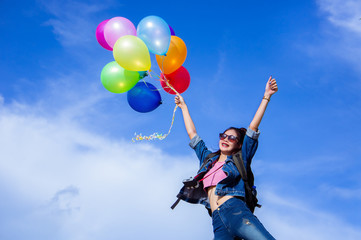 The jumping girl holds a ball of light color on a bright sky background