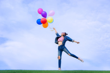 The jumping girl holds a ball of light color on a bright sky background