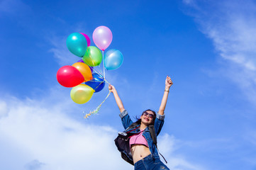 The jumping girl holds a ball of light color on a bright sky background