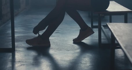 CU DOLLY IN Caucasian female athlete preparing for a workout in a gym locker room, tying shoelaces before training session. 4K UHD 60 FPS SLOW MOTION